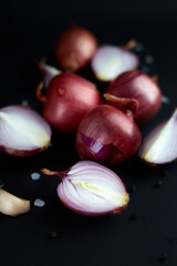 Red onion on black background Whole and sliced onions, salt, garlic and spices. Flat lay, copy space