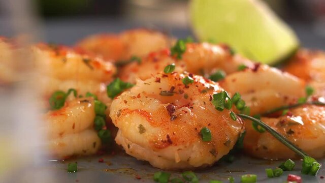 Close up of fried prawns in sweet and sour sauce with garlic spices and seasonings is sprinkled with green chopped onions. Cooking food. Seafood