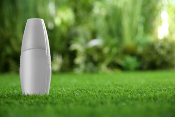Bottle of insect repellent spray on green grass. Space for text