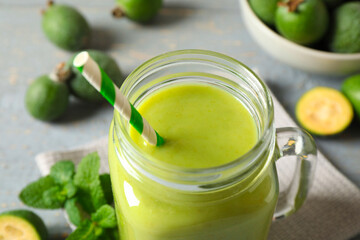 Fresh feijoa smoothie in mason jar on grey table, closeup