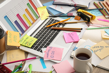 Laptop, notes and office stationery in mess on desk. Overwhelmed with work