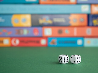 Two dice on the background of board game boxes. Dice games for kids, tweens and adults