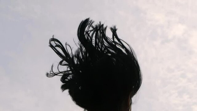 Slow motion of dark haired woman jumping in the sky. Flying and shaking cyrly hair.
