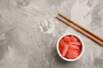 Spicy pickled ginger and chopsticks on grey table, flat lay. Space for text