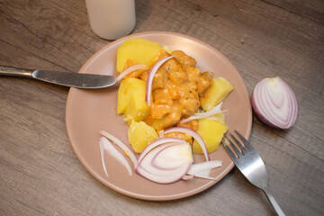 Potatoes with sauce and onions on a plate with a candle next to it. Bad romance.