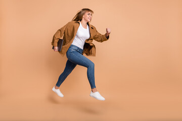Full length profile side photo of charming nice young lady jump up run empty space isolated on pastel beige color background