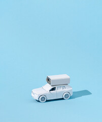 White toy car with white battery on it. Creative blue background. Minimal concept with negative space.