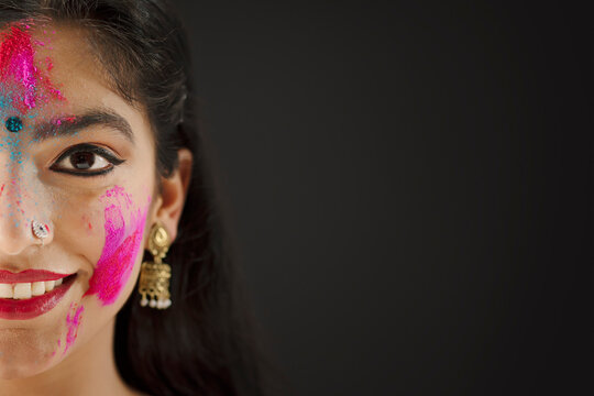 CLOSE SHOT OF ONE SIDE OF A FACE OF A YOUNG WOMAN WITH HOLI COLOURS ON HER	