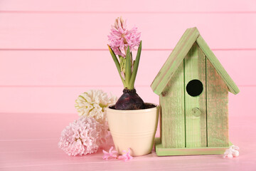 Stylish bird house and fresh hyacinths on pink wooden table
