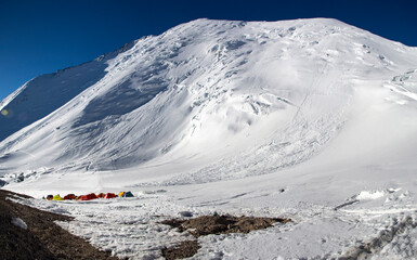 high mountain peak with high camp under the range in bluebird weather 