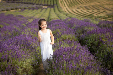 Fototapeta na wymiar Cute little girl having fun in a lavender field