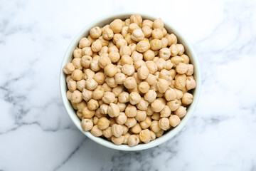 Chickpeas in bowl on white marble table, top view