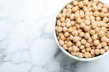 Chickpeas in bowl on white marble table, top view. Space for text