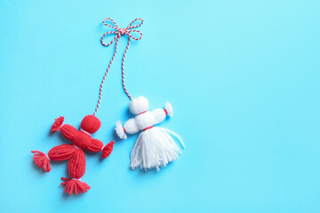 Traditional martisor shaped as man and woman on light blue background, top view with space for text. Beginning of spring celebration