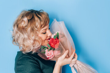Woman in dress holding beautiful bouquet of flowers in front of blue background. Holiday gift valentine day, 14 february, March 8, Mothers day