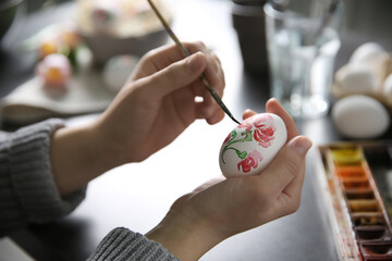 Woman painting Easter egg at black table, closeup