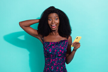 Photo portrait woman smiling surprised staring using app on cellphone isolated on vivid turquoise color background