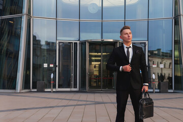 Portrait young man businessman with briefcase background business building corporate company, looking away, lifestyle. Male banker standing out from office located in financial district. Copy space