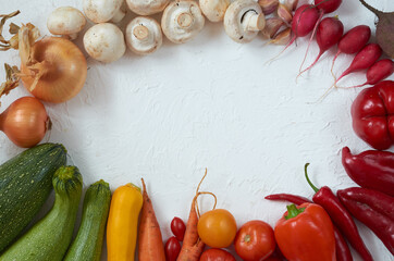 Frame of various vegetarian ingredients ready for cooking on the white table. Organic healthy food: colorful vegetables on the white background. Top view with copy space for text