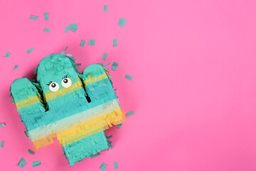 Bright cactus pinata and confetti on pink background, flat lay. Space for text