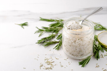 Glass jar of white sea salt and rosemary, fresh green rosemary on the white table.Empty space © uaPieceofCake