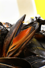 Food delivery in plastic packaging to your home. Mussels in sauce in foil and plastic container on yellow background