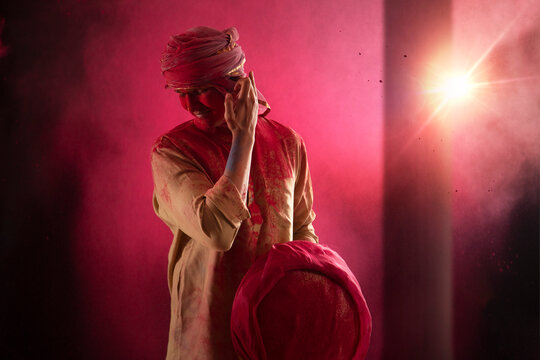 A YOUNG MAN COVERED IN HOLI COLOURS BENDING AND TOUCHING EARS - Powered by Adobe