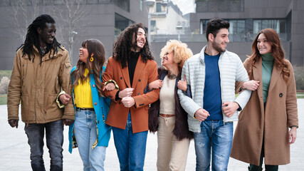 group of multiethinc couples walking and chatting, six friends smiling and laughing, concepts of inclusion, diversity and aggregation of the millennials generation