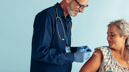 Doctor putting band-aid after giving flu shot to woman