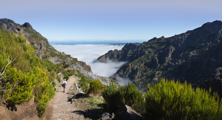 Above the clouds on a mountain trail. Colorful mist in valley. Trekking from Pico do Arieiro to Pico Ruivo, Madeira island, Portugal. 