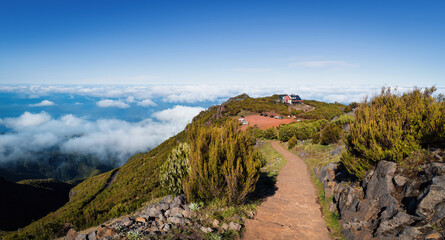 Fototapeta na wymiar Above the clouds on a mountain trail. Colorful mist in valley. Trekking from Pico do Arieiro to Pico Ruivo, Madeira island, Portugal. 