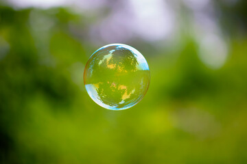 multicolored soap bubble on a green background. Soap bubble. Isolated on green, in spring or summer. reflex, detailed, close-up. multi-colored ball flies. holiday concept, childhood