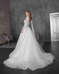 Full length bride portrait. Elegant woman with hairstyle in white wedding dress spinning in grey...
