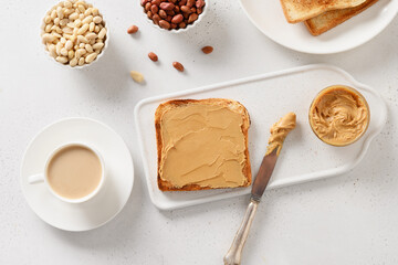 Morning with tasty heathy breakfast of coffee and crispy toast with peanut paste on white table....