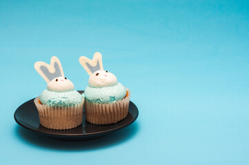 Cupcakes on a plate. Blue background. Minimalistic composition. Easter concept