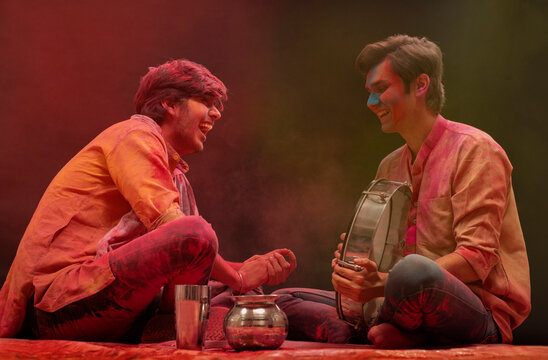 TWO FRIENDS HAPPILY LAUGHING TOGETHER AND PLAYING DAFLI DURING HOLI FESTIVAL	