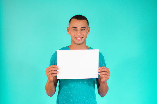 Handsome Young Latin Man Holding A Sheet Of Paper Over Green Background