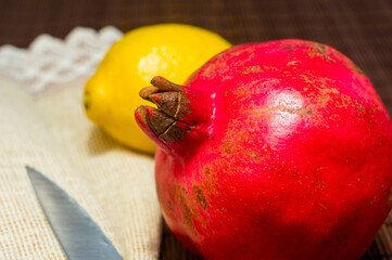 Large fresh fruit of pomegranate and lemon with a woven napkin and a knife on a bamboo mat, still...