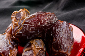Big luxury dried date fruit in bowls on the dark surface, kurma ramadan kareem concept, close up.