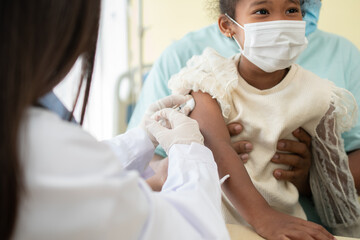Asian doctor user syringe needle for injection vaccinate,  African American children are being...