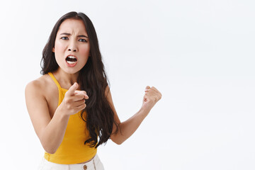 Its all your fault. Angry and upset outraged east-asian woman blame someone and complaining, frowning making furious grimace as pointing finger at camera, make accusations and fighting