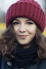 Portrait of a beautiful girl in a crimson hat, she smiles and rejoices