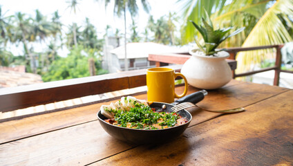 Szakszuka, jajka smażone w pomidorach na patelni, pyszne śniadanie na stole z tropikalnym...