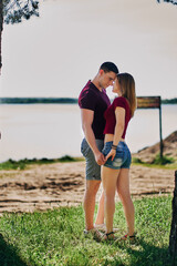 Young couple in love kissing by the lake. vertical