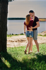 Romantic couple of lovers hug and kiss on the shore of the lake, river. vertical