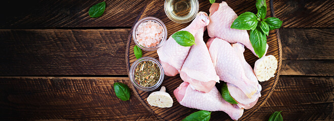 Raw chicken drumsticks with spices. Raw chicken legs with spices on a wooden  background. Top view,...