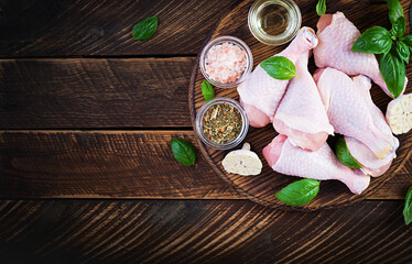 Raw chicken drumsticks with spices. Raw chicken legs with spices on a wooden  background. Top view, overhead, copy space.