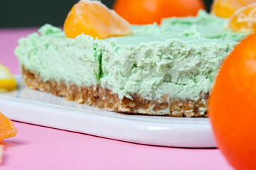 Slice of green sicilian pistachio cake stuffed with vanilla, almonds and nuts on a white plate
