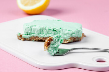 
Raw vegan cheesecake with lime and cashew nuts. Vegan raw cheesecake on a pink background without flour and sugar