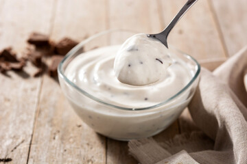 Stracciatella yogurt in transparent bowl on wooden table